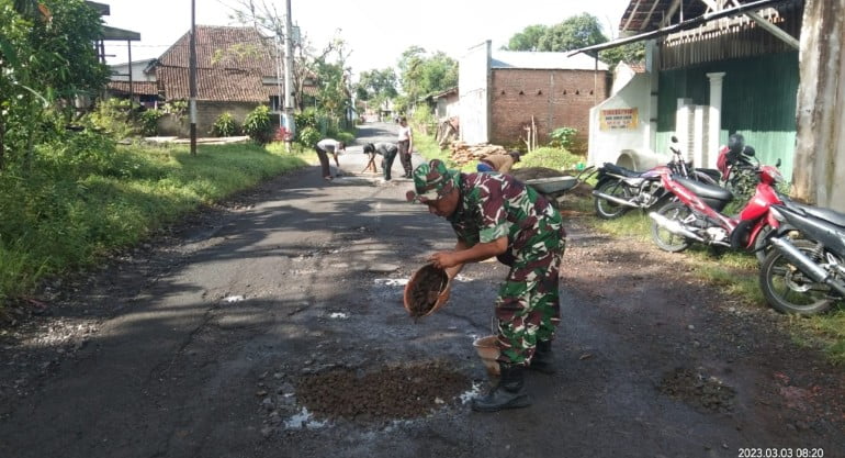 Sikap Peduli Babinsa Serda Epi Bersama Warga Timbun Jalan Berlubang