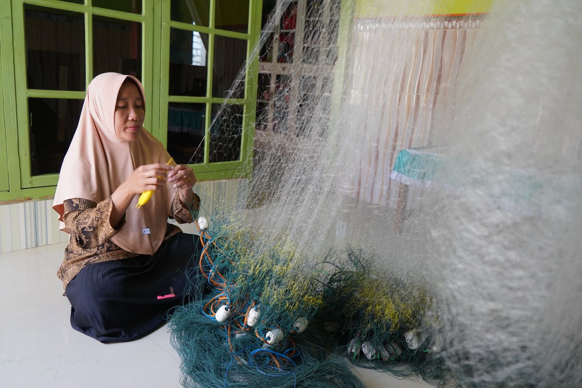 Ibu Asih, salah satu local champions perempuan nelayan rajungan, memperbaiki jaring yang digunakan untuk menangkap ikan Foto: Adam Putra/CTC