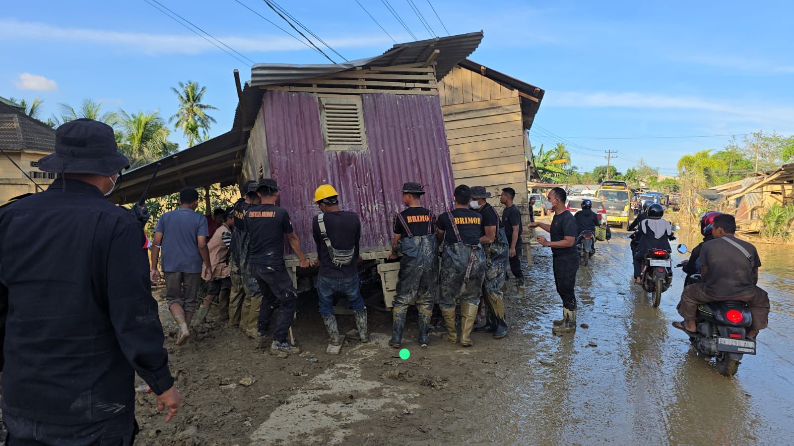 Bahu Membahu , Brimob Pindahkan Rumah Terseret Banjir Yang Melintang di Jalan Nasional Tamiang - Langsa